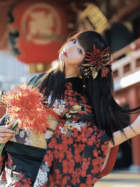 Woman in Asakusa wearing a black furisode with red flowers and holding red spider lilies